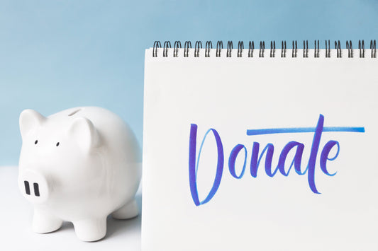 Salvadanaio a forma di maialino con accanto un block notes con sù scritto Donate